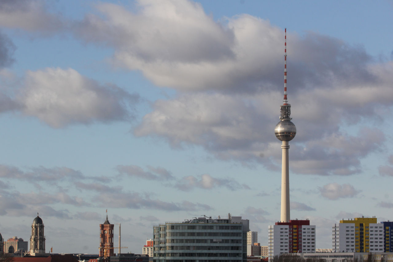 Communications tower in city against sky