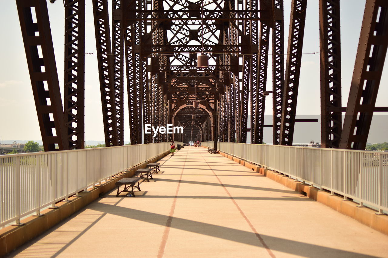 Footbridge in city against sky