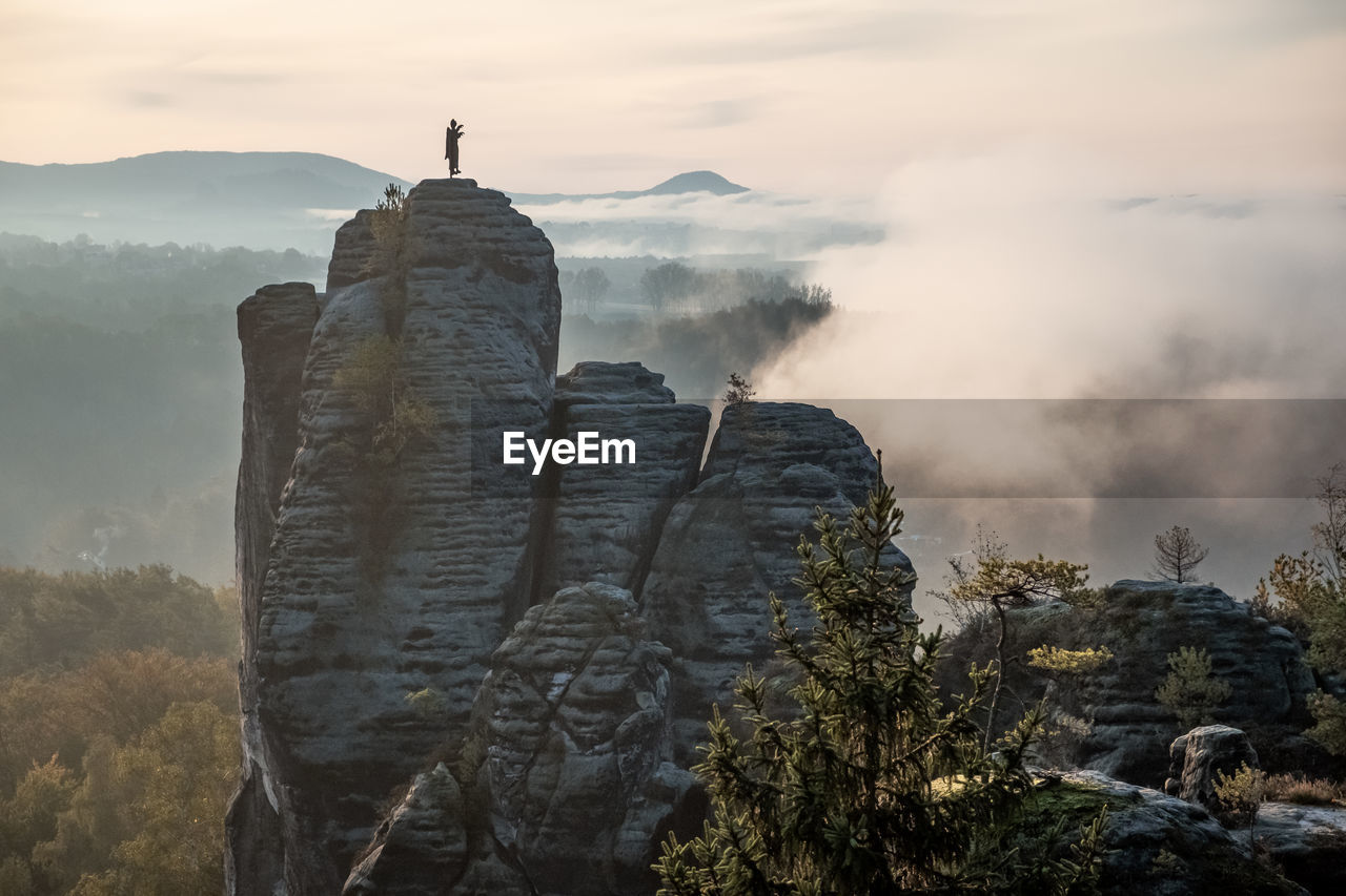 Rock formations on mountain against cloudy sky