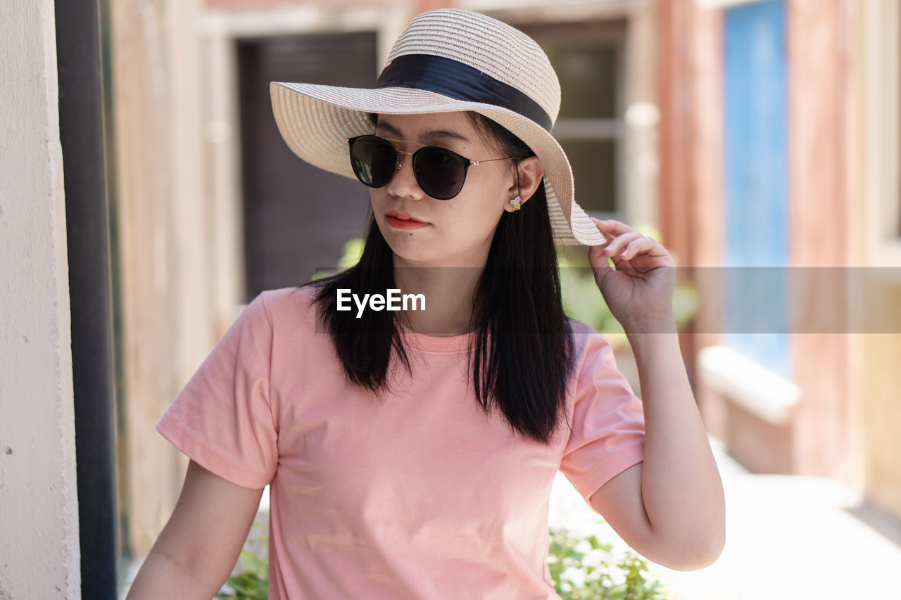 Portrait of young woman wearing hat while standing outdoors