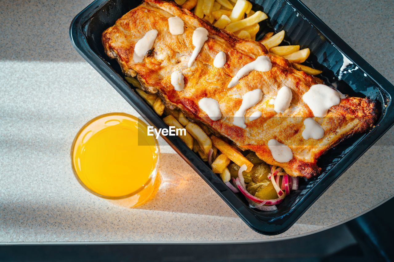 High angle view of pork ribs and fries and juice on table