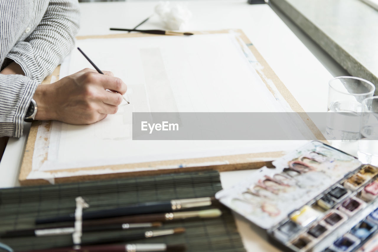 Cropped image of artist painting on canvas at creative office