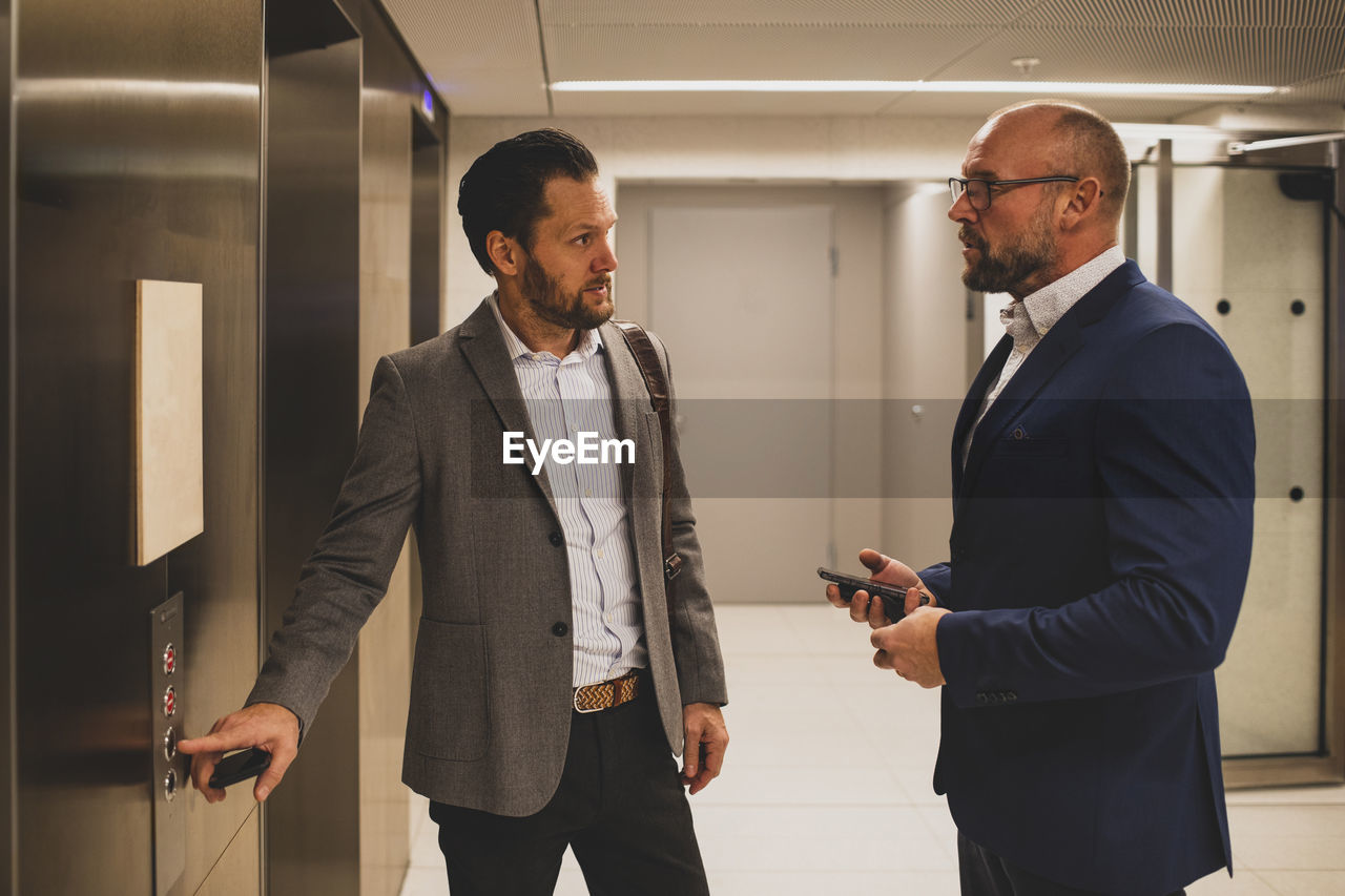 Businessmen talking near office elevator