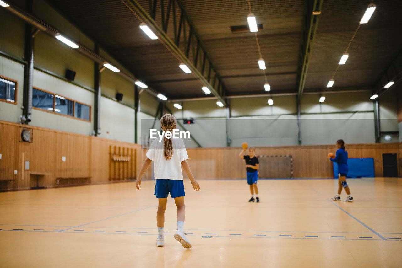 Female friends playing handball in sports court