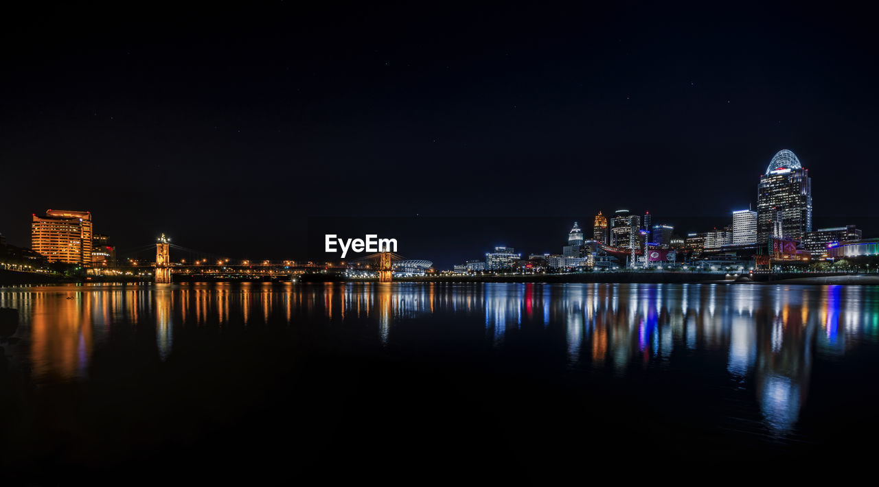 REFLECTION OF ILLUMINATED BUILDINGS IN RIVER AGAINST SKY