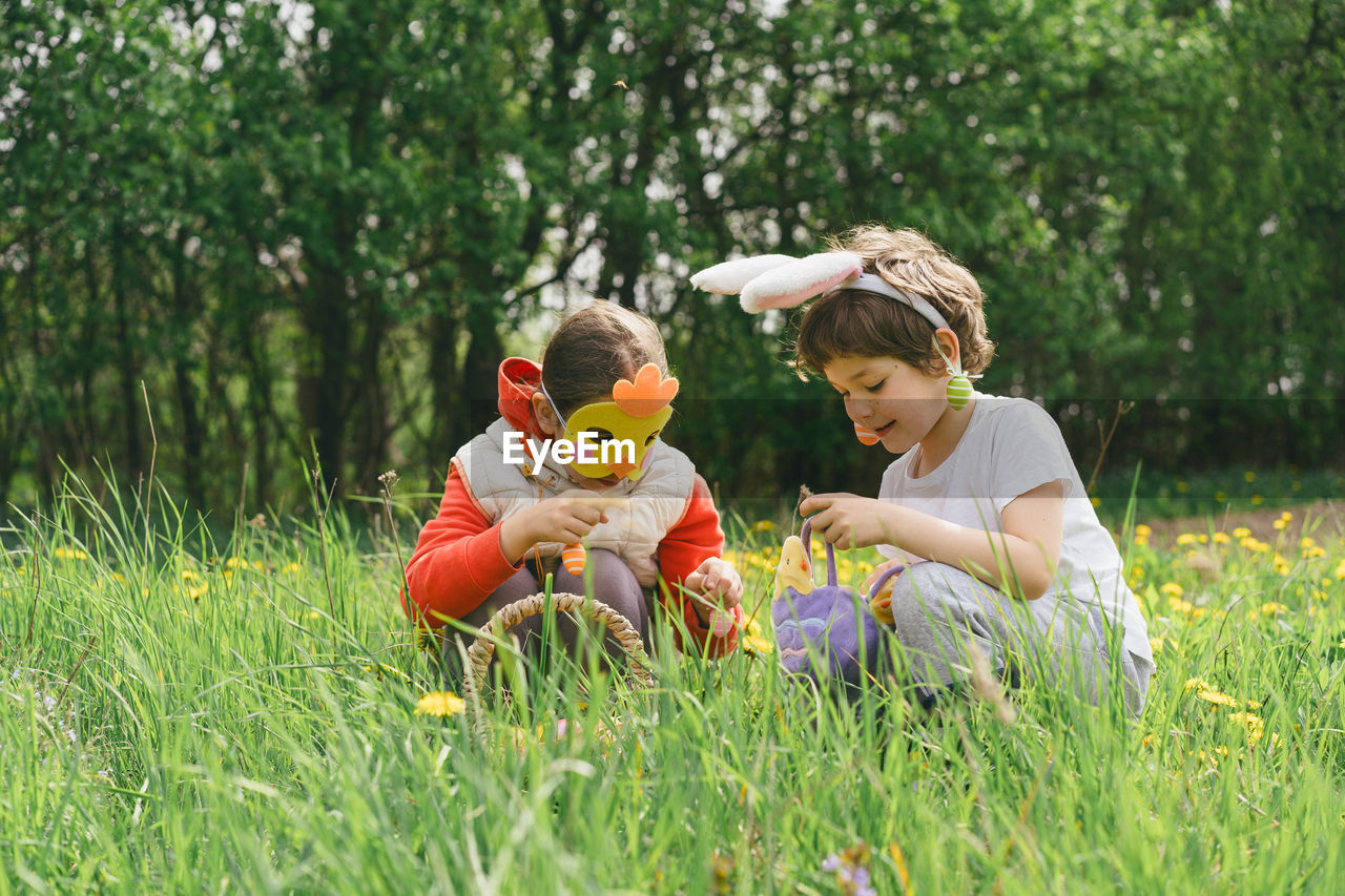 side view of mother and daughter sitting on grassy field