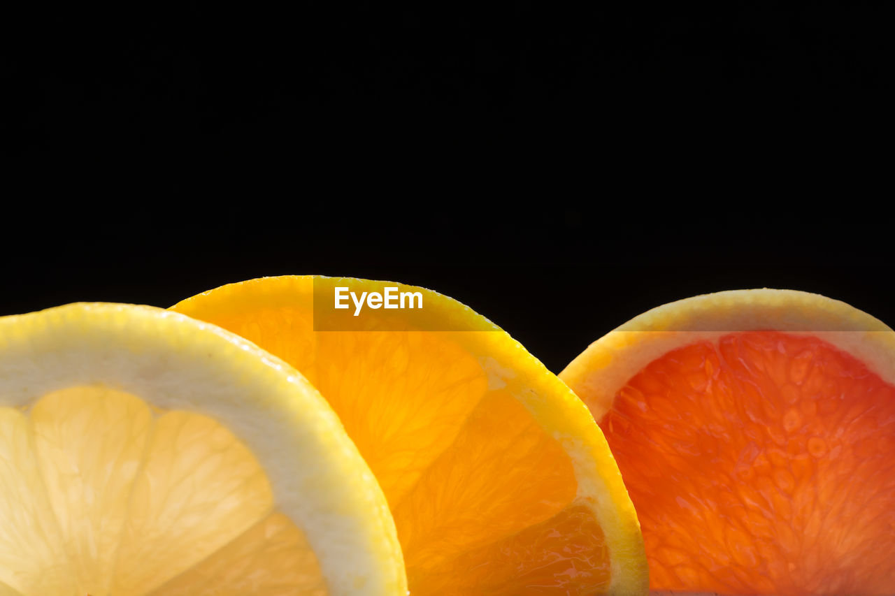 CLOSE-UP OF ORANGE SLICES AGAINST BLACK BACKGROUND