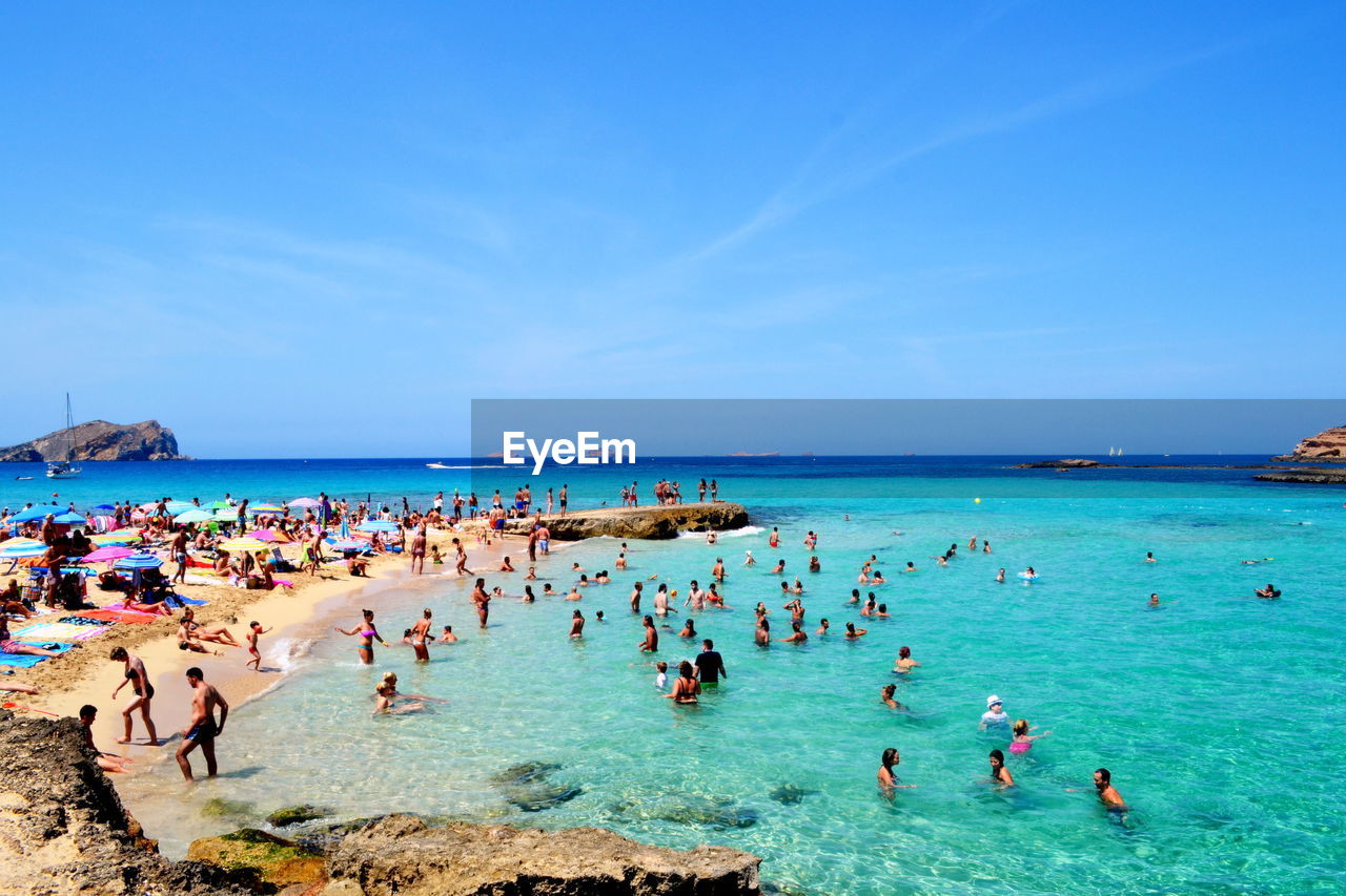 PEOPLE AT BEACH AGAINST BLUE SKY