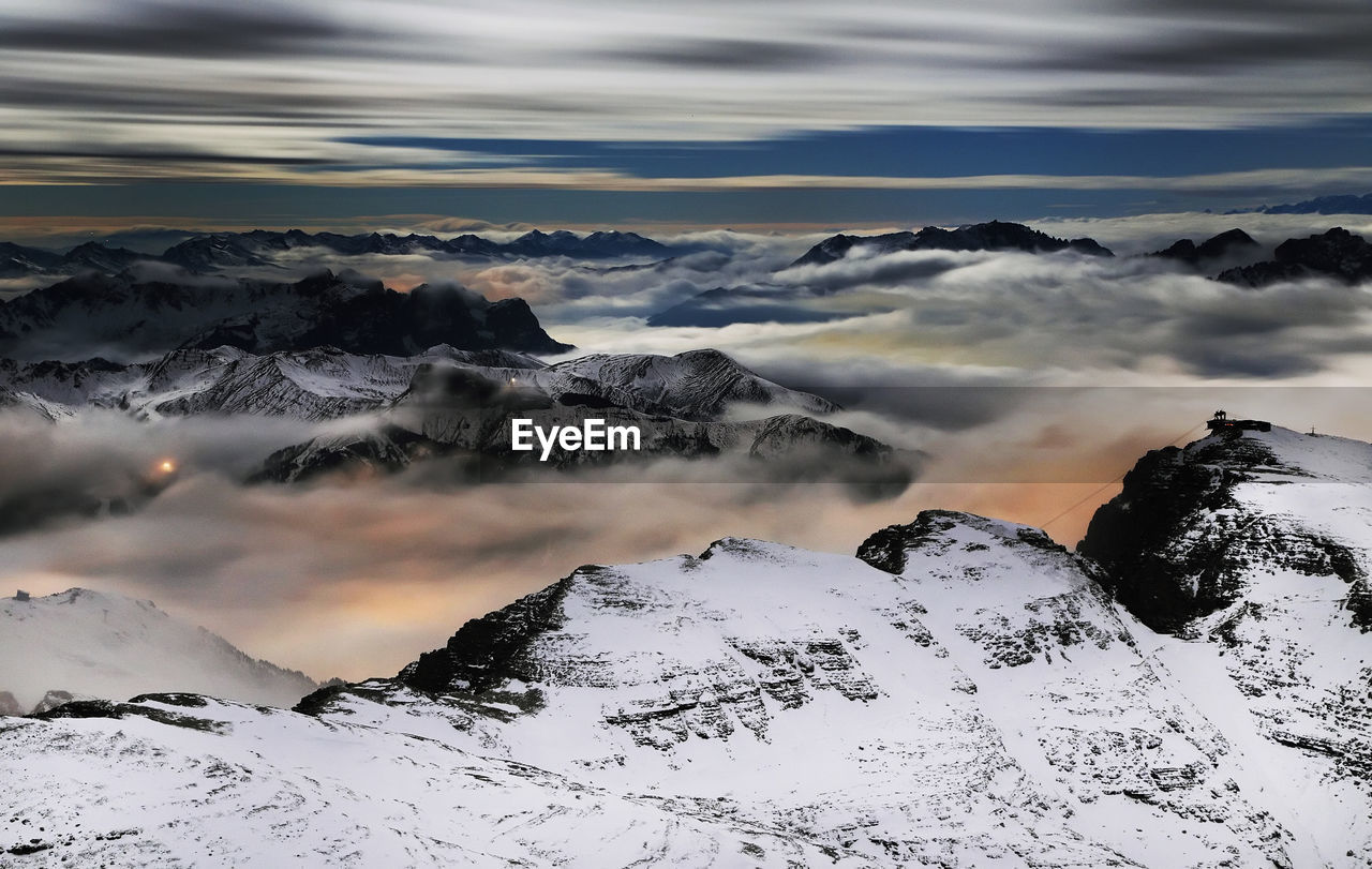 Scenic view of clouds covering snowcapped mountains