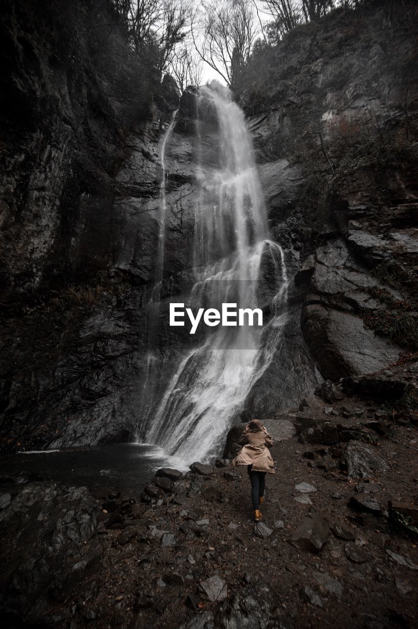 Rear view of woman against waterfall