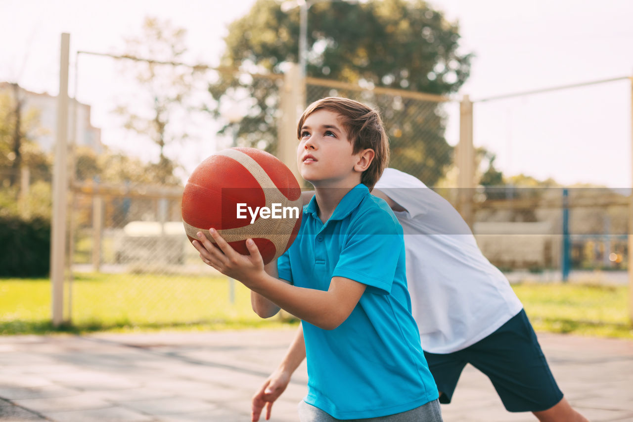 Two teenage boys play basketball on the playground. athletes fight for the ball in the game. healthy