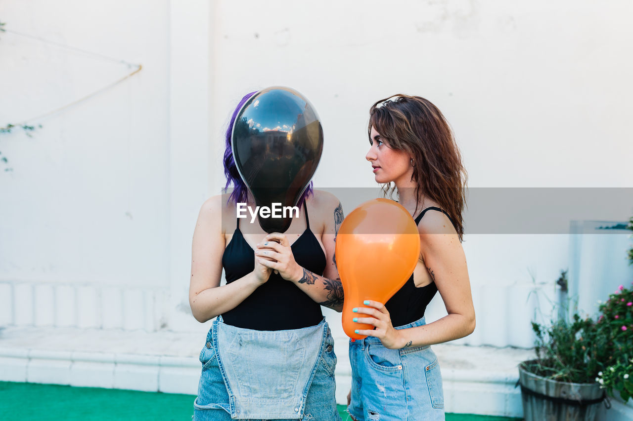 Lesbian couple holding balloon standing outdoors