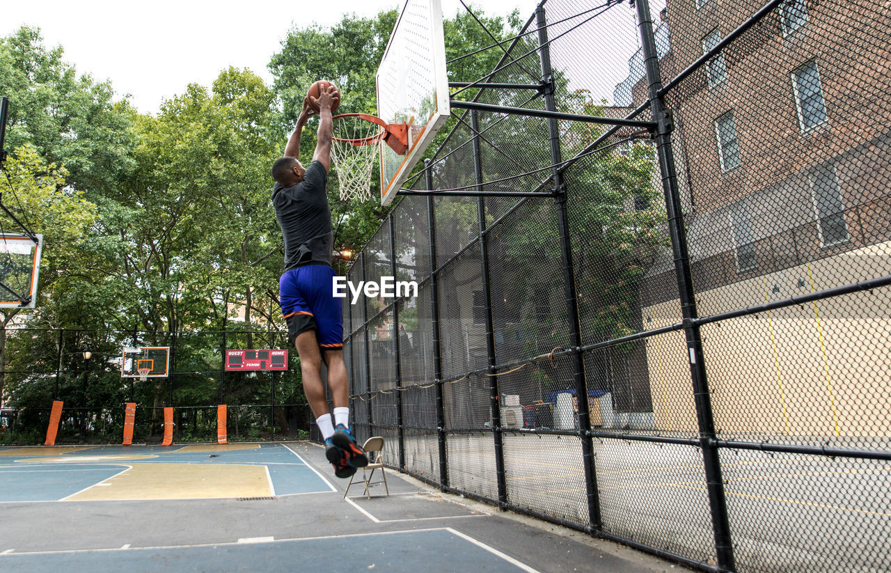 Young man practicing basketball in court