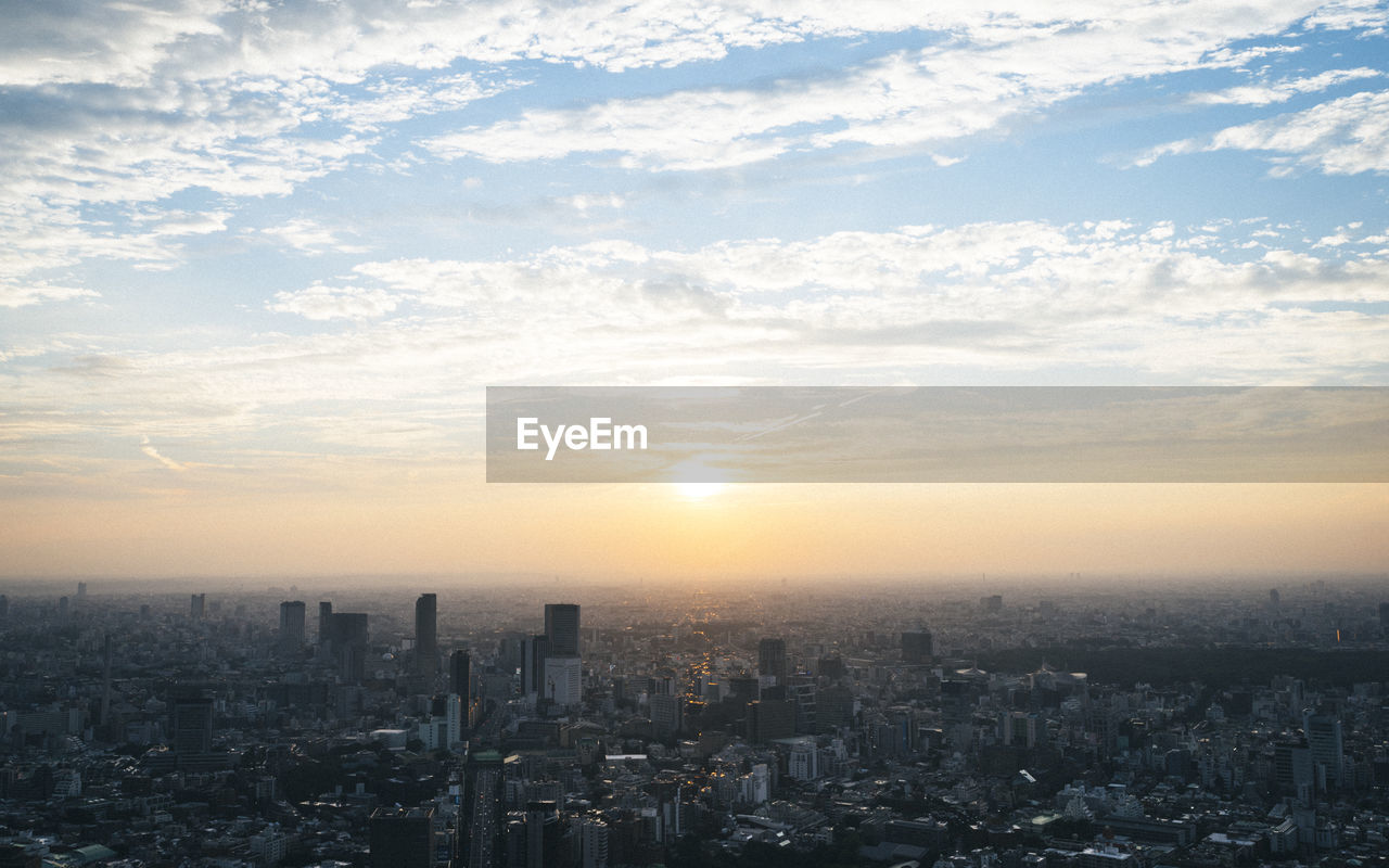 Aerial view of cityscape against cloudy sky