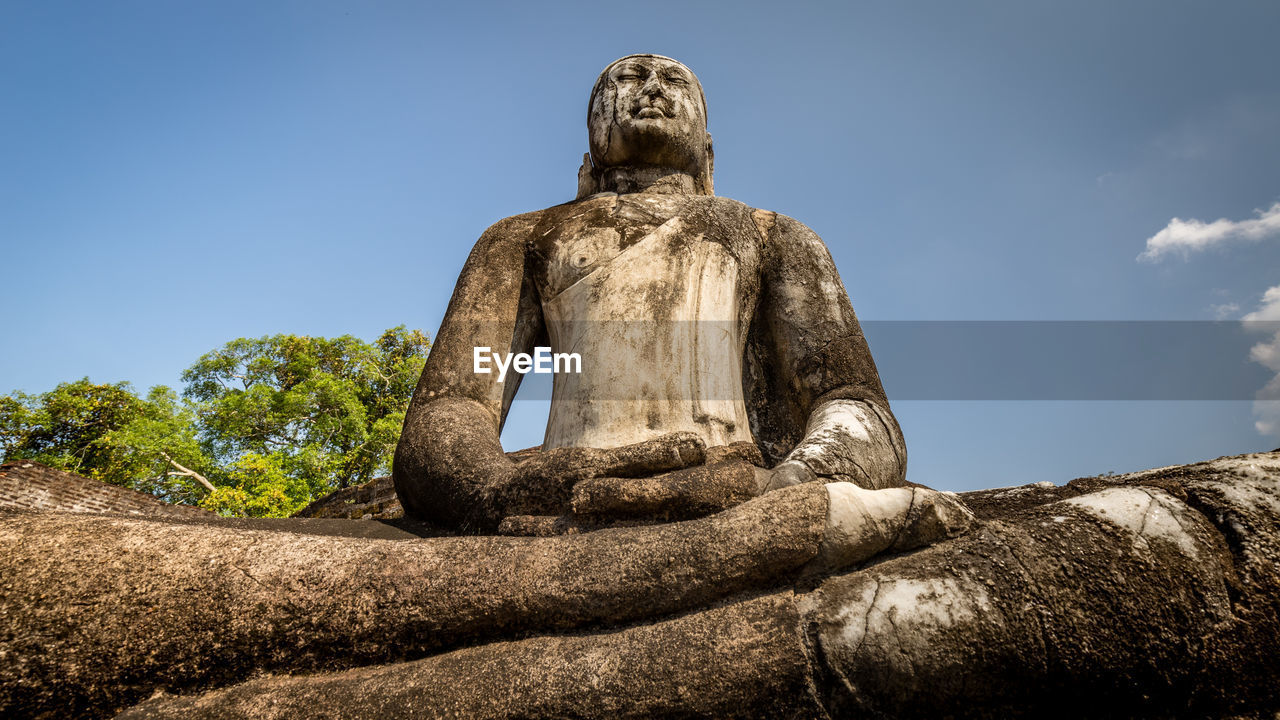 Low angle view of buddha statue against sky