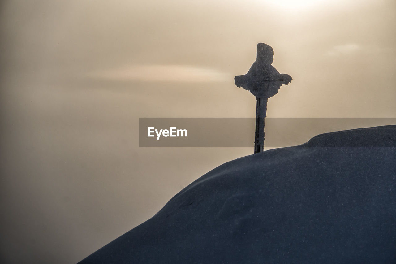 Snowcapped mountain cross in the sunset