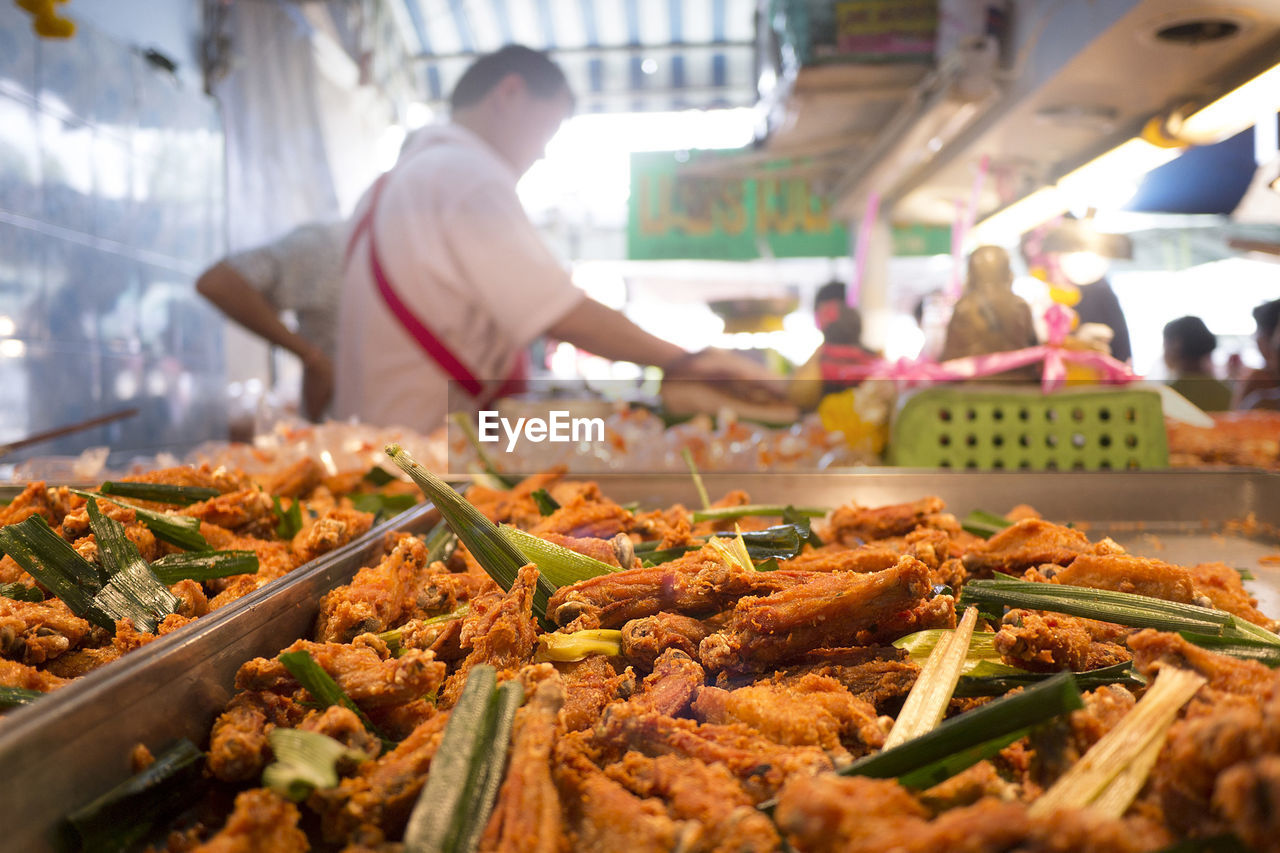 Close-up of fried chicken with lemon grass in tray for sale