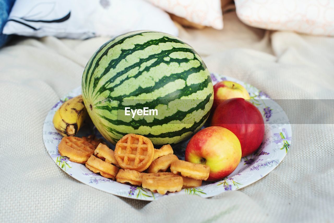 Close-up of fruits and waffles in plate on bed at home