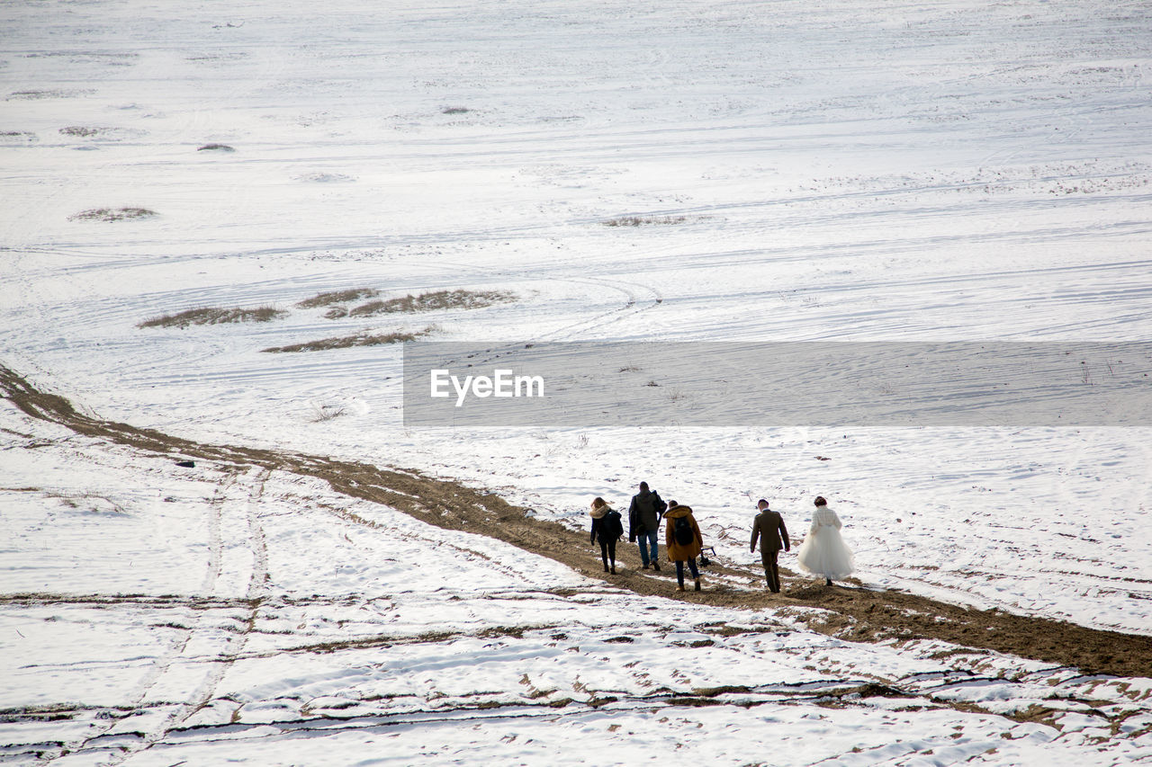 Rear view of people walking on snow covered land