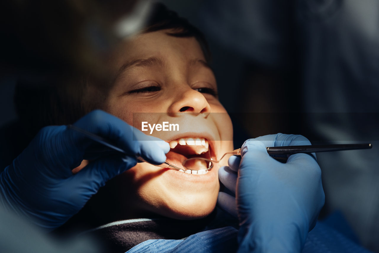 Dentist operating cheerful boy in medical clinic