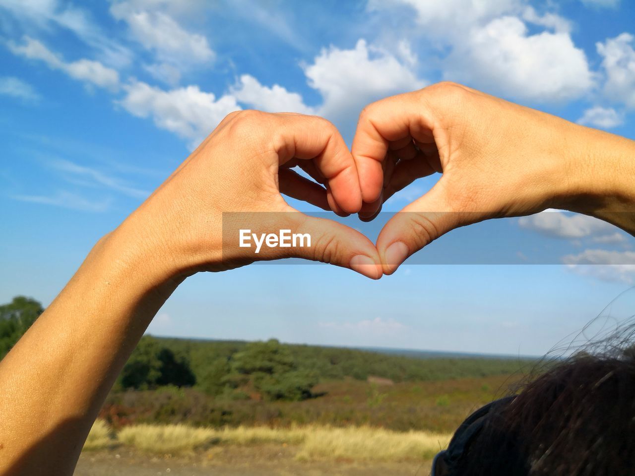 Close-up of hands forming heart shape against sky