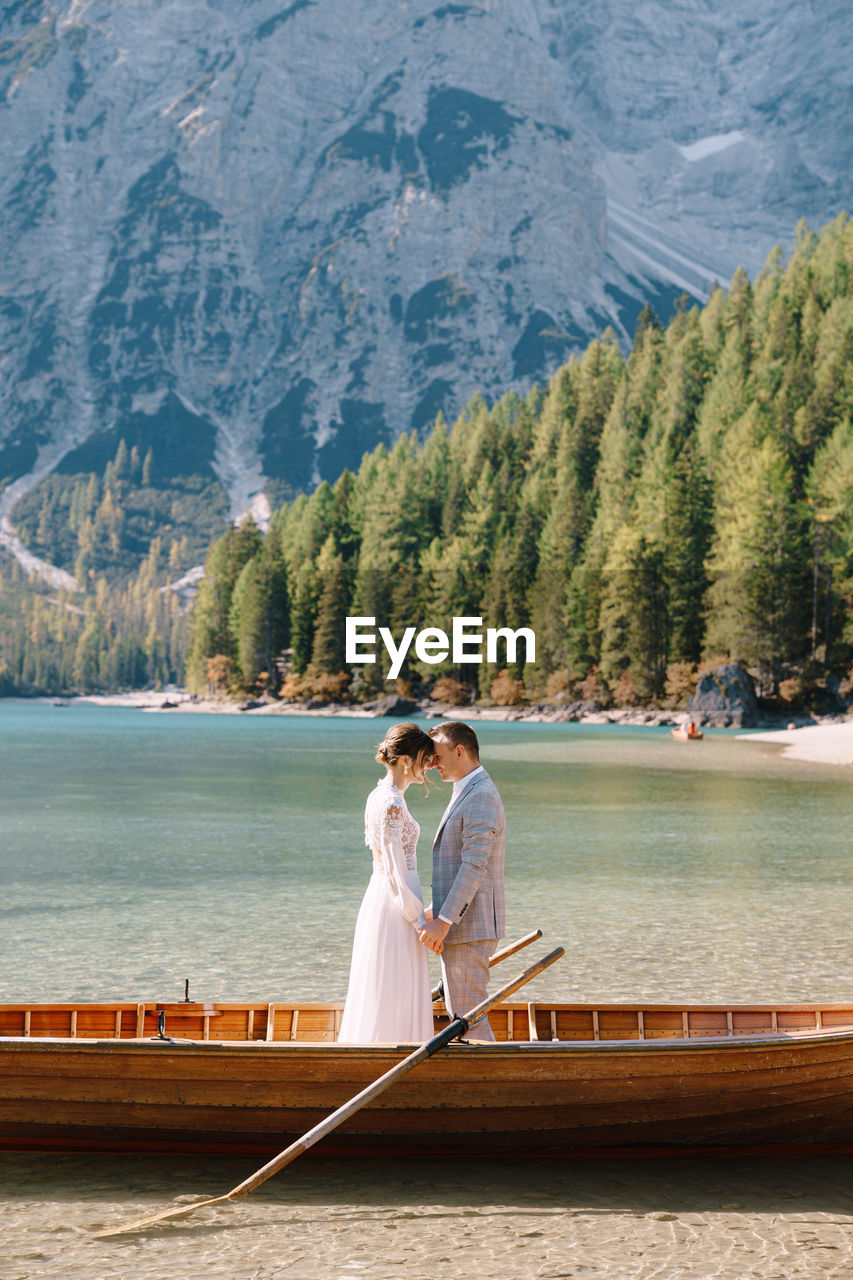 WOMAN STANDING ON LAKE BY MOUNTAINS