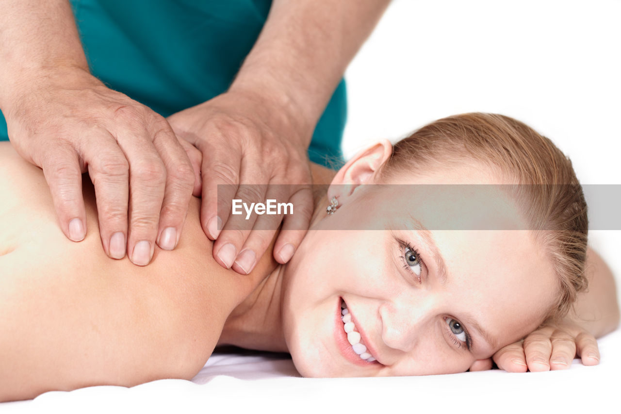 Cropped hands of masseur giving massage to beautiful smiling woman