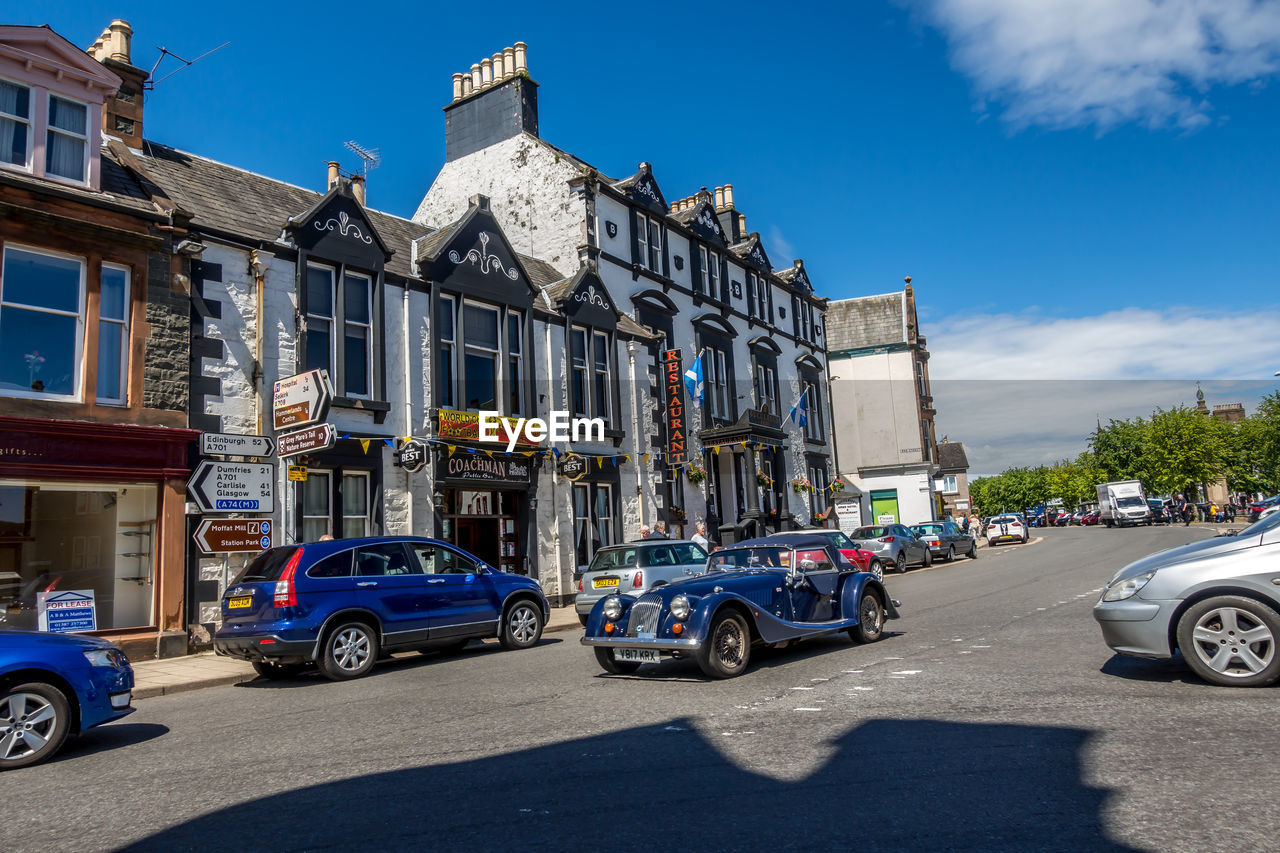 CARS ON ROAD BY BUILDINGS IN CITY