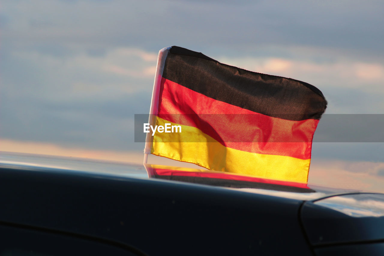 German flag on car against sky during sunset