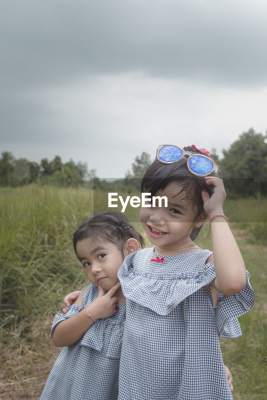 Two cute little girls hugging outdoors in a park