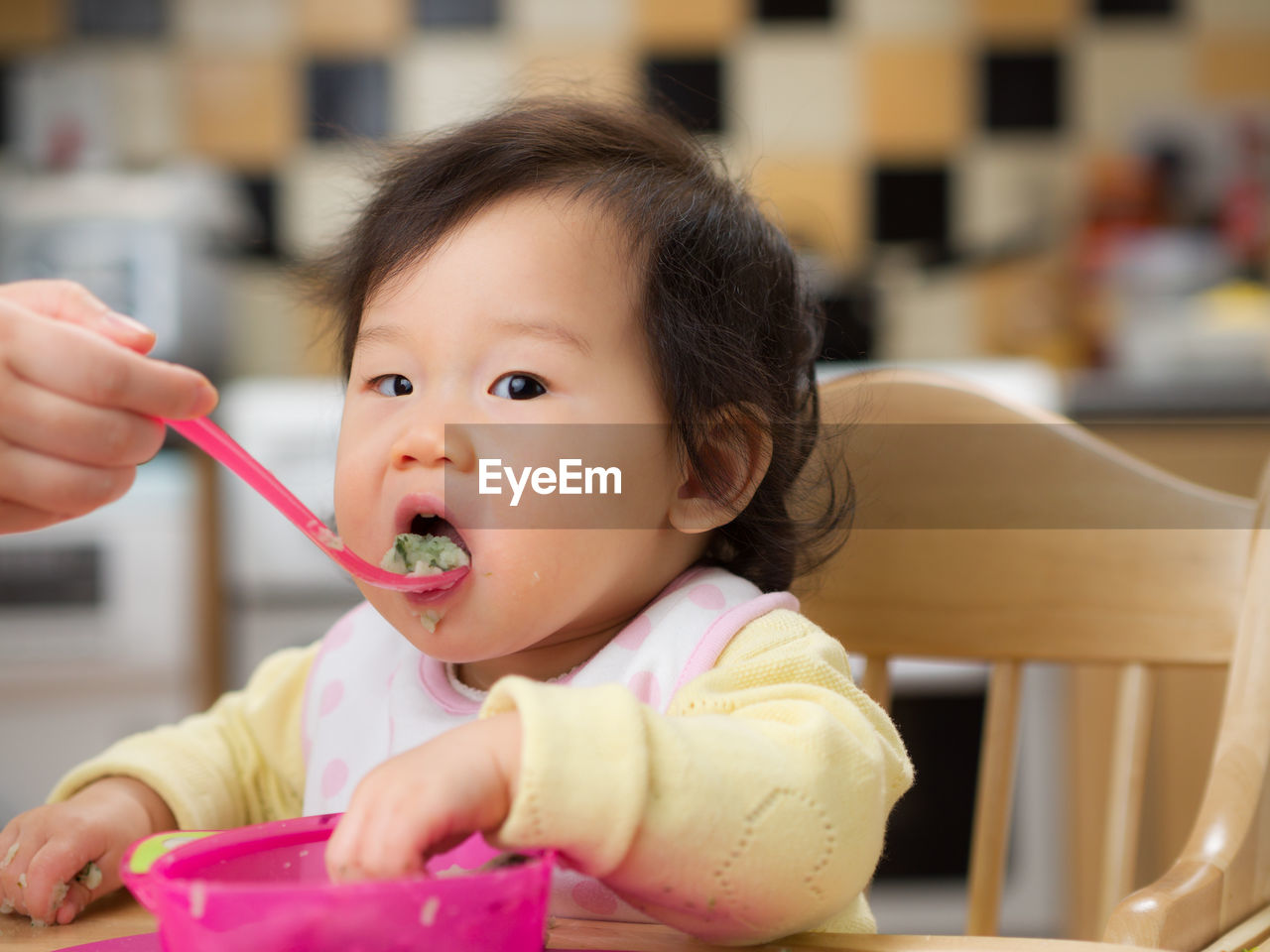 Close-up portrait of cute baby girl eating food at home