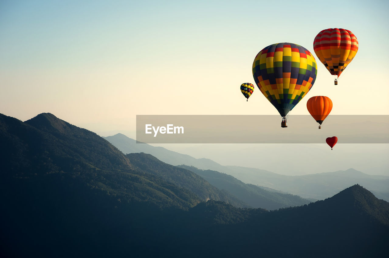 Hot air balloons flying in mountains against clear sky