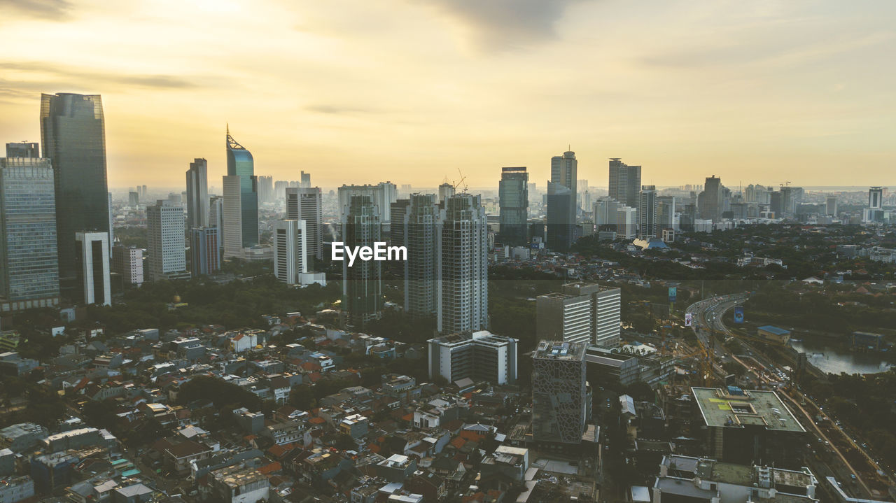 Aerial view of modern buildings in city against sky during sunset