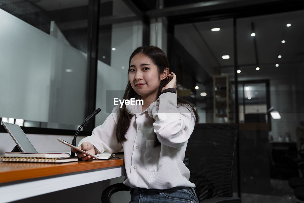 Portrait of young woman using phone at office