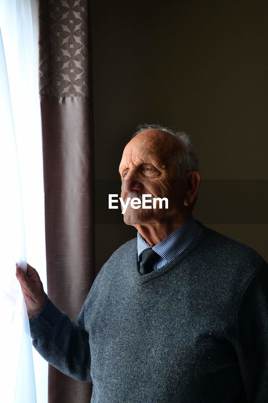 Senior man standing by window at home