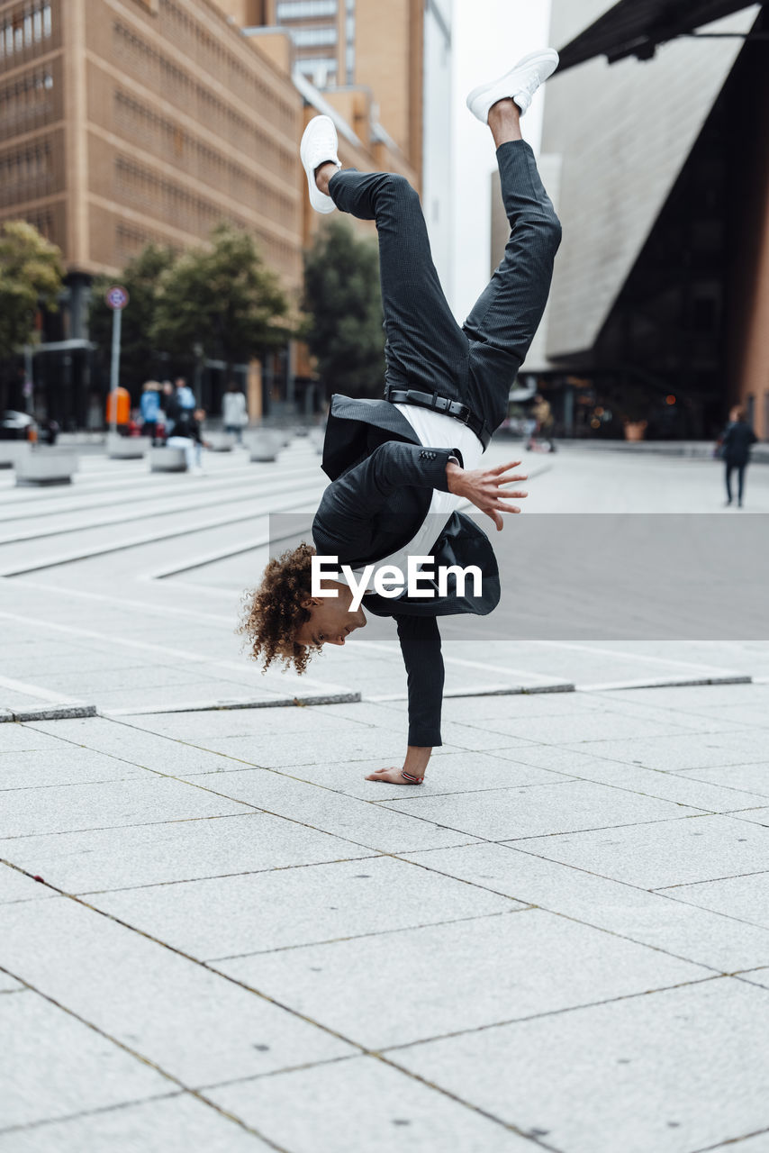 Excited businessman doing handstand on square at potsdamer platz