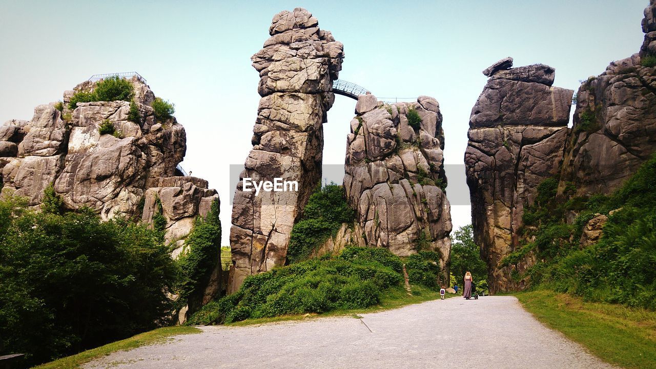 REAR VIEW OF MAN WALKING ON ROCKS