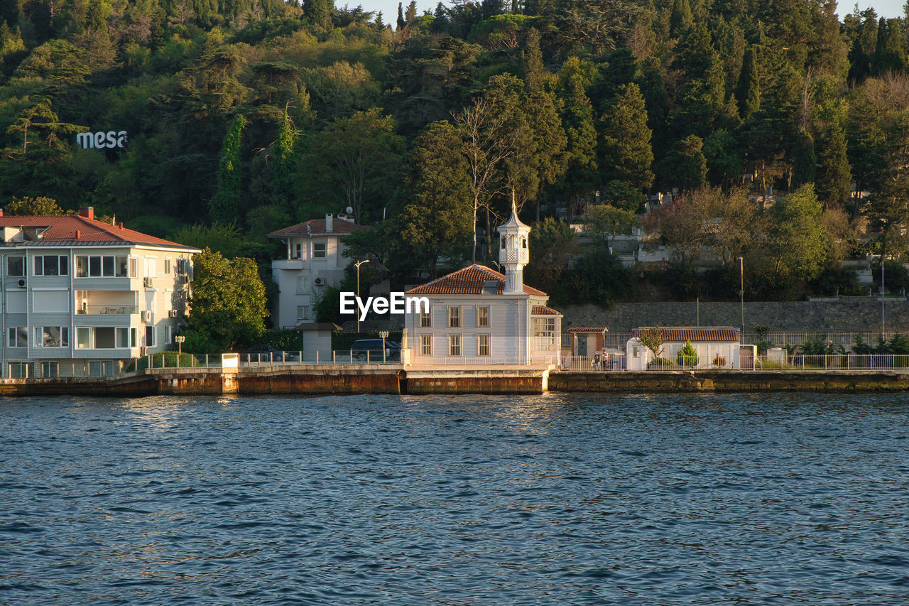 Houses by river and buildings in city