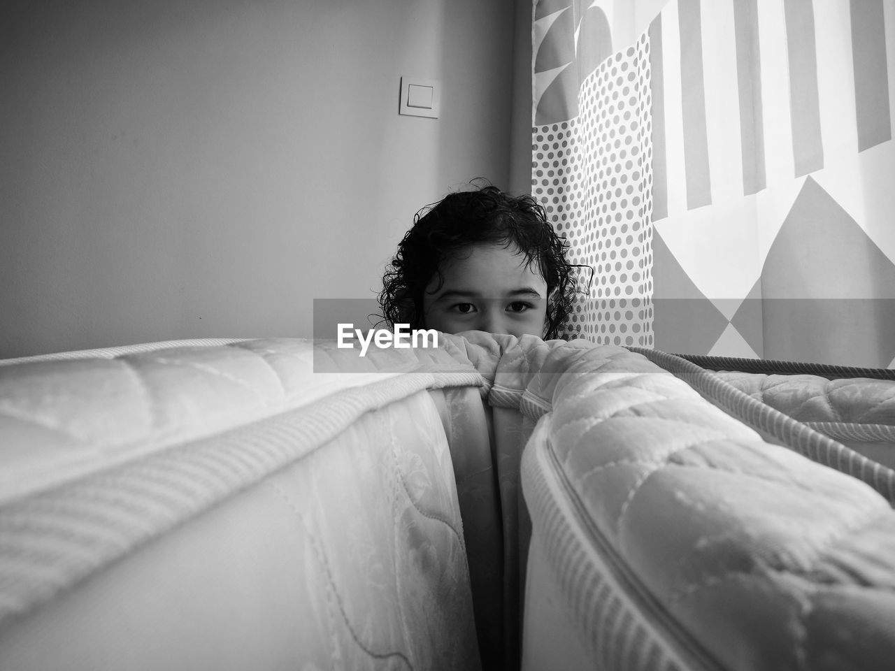 Girl hiding behind mattress