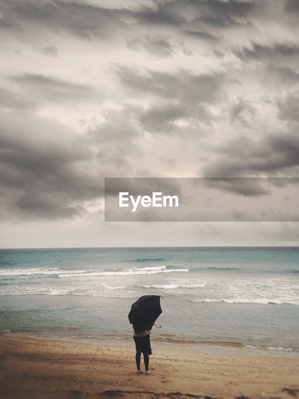 Woman standing on beach against sky