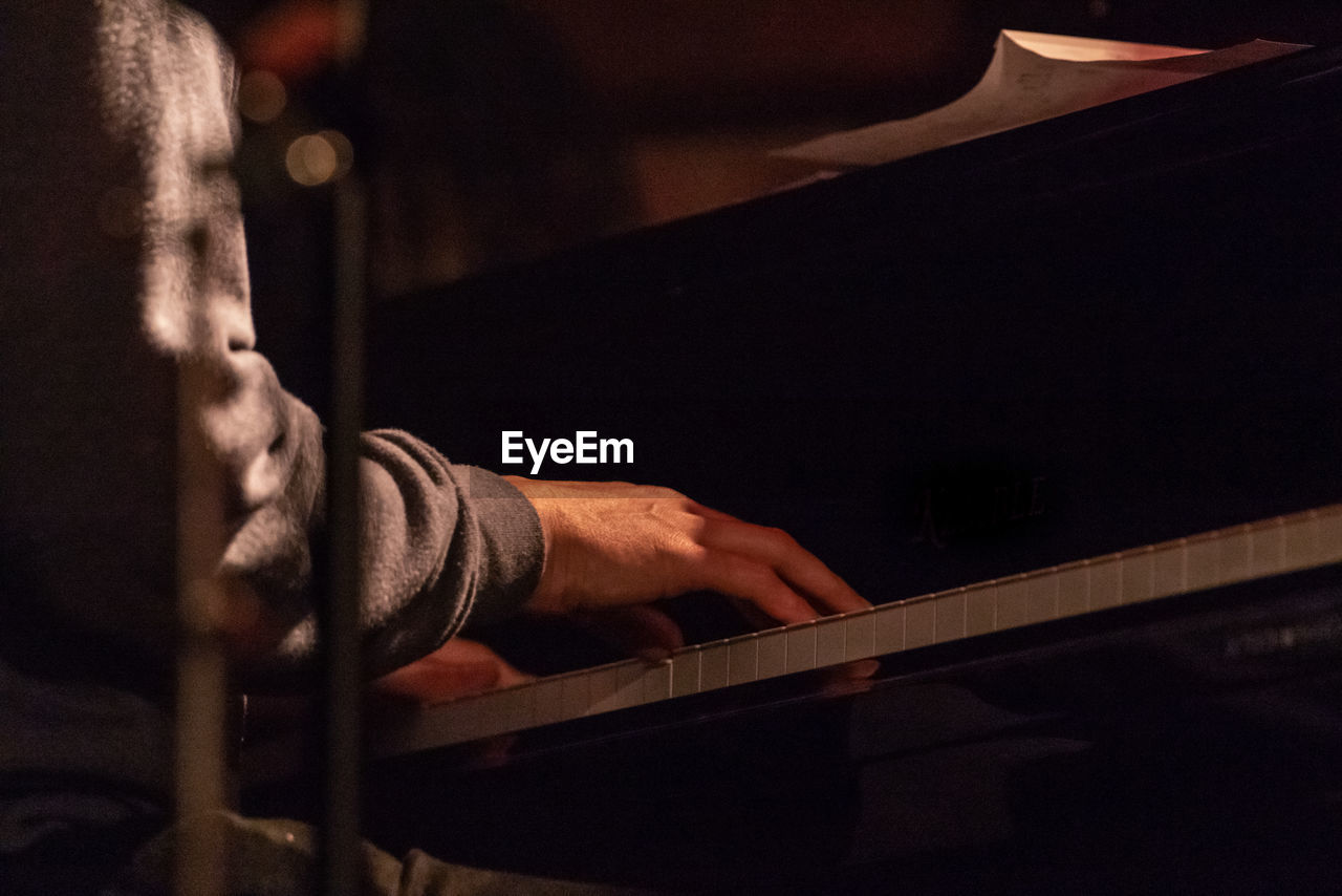 Midsection of man playing piano at night