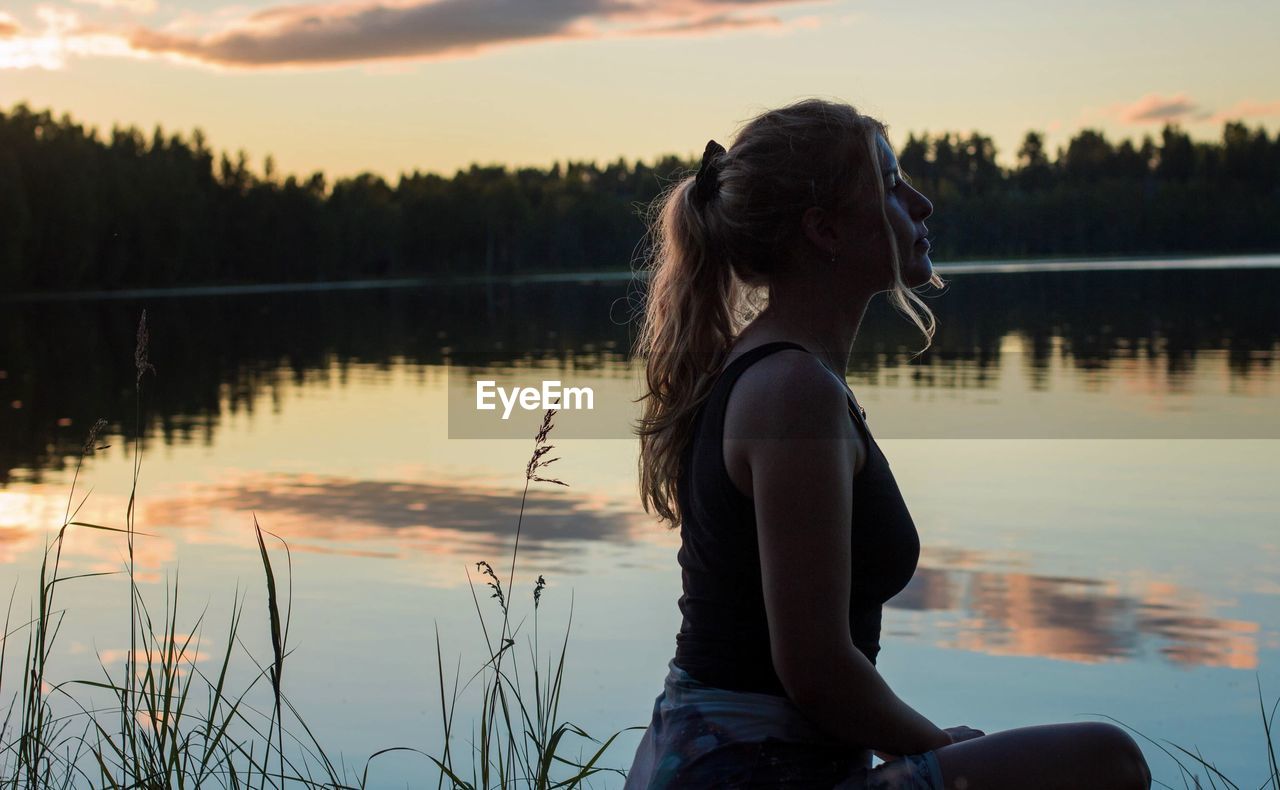 WOMAN LOOKING AT LAKE DURING SUNSET