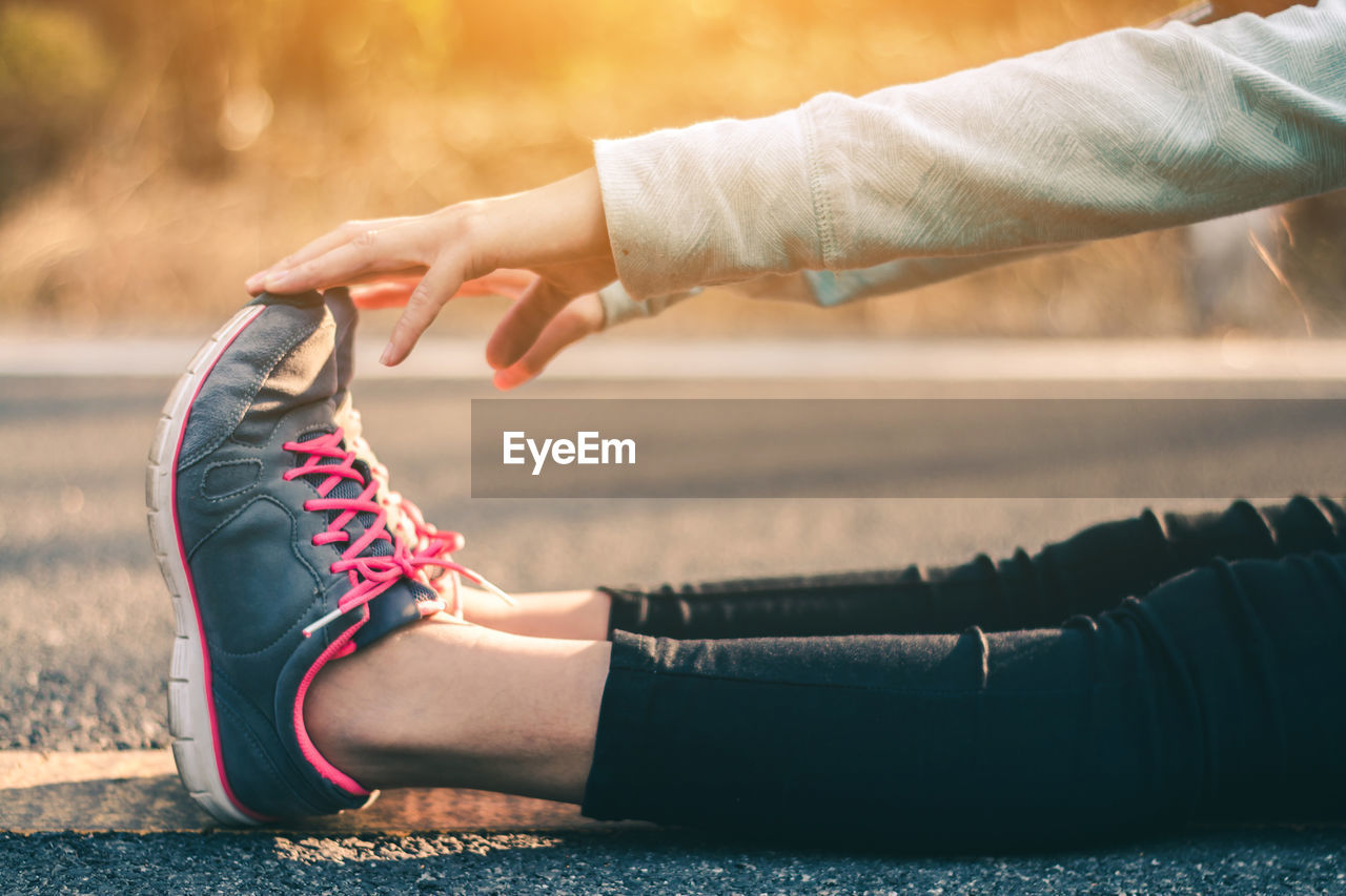 Low section of woman exercising on road