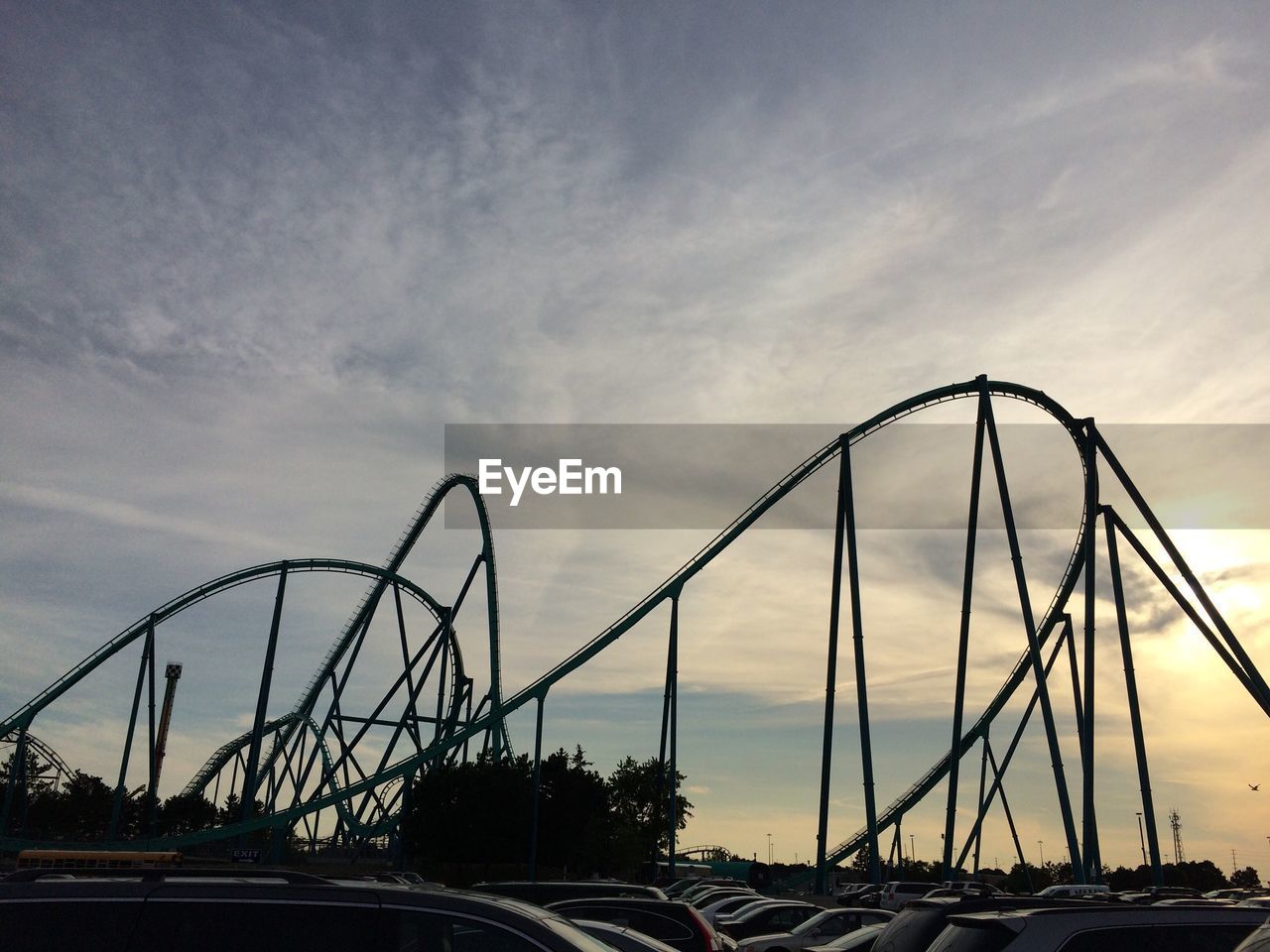 Low angle view of silhouette rollercoaster against cloudy sky during sunset
