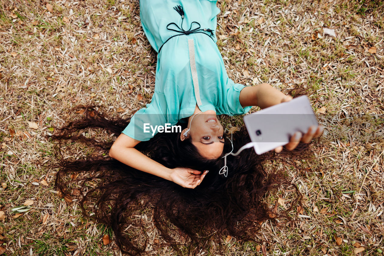 Smiling beautiful woman photographing through camera while lying on grassy field