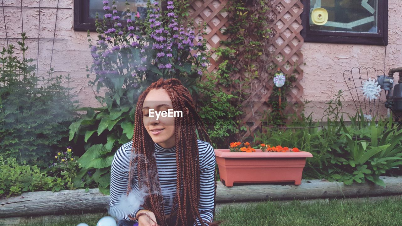 Young woman with braided hair sitting in yard