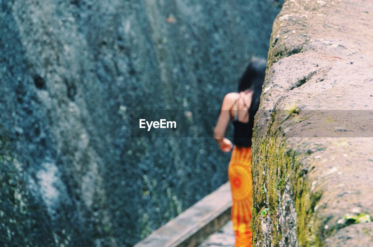 Rear view of woman walking on footpath amidst rock formation