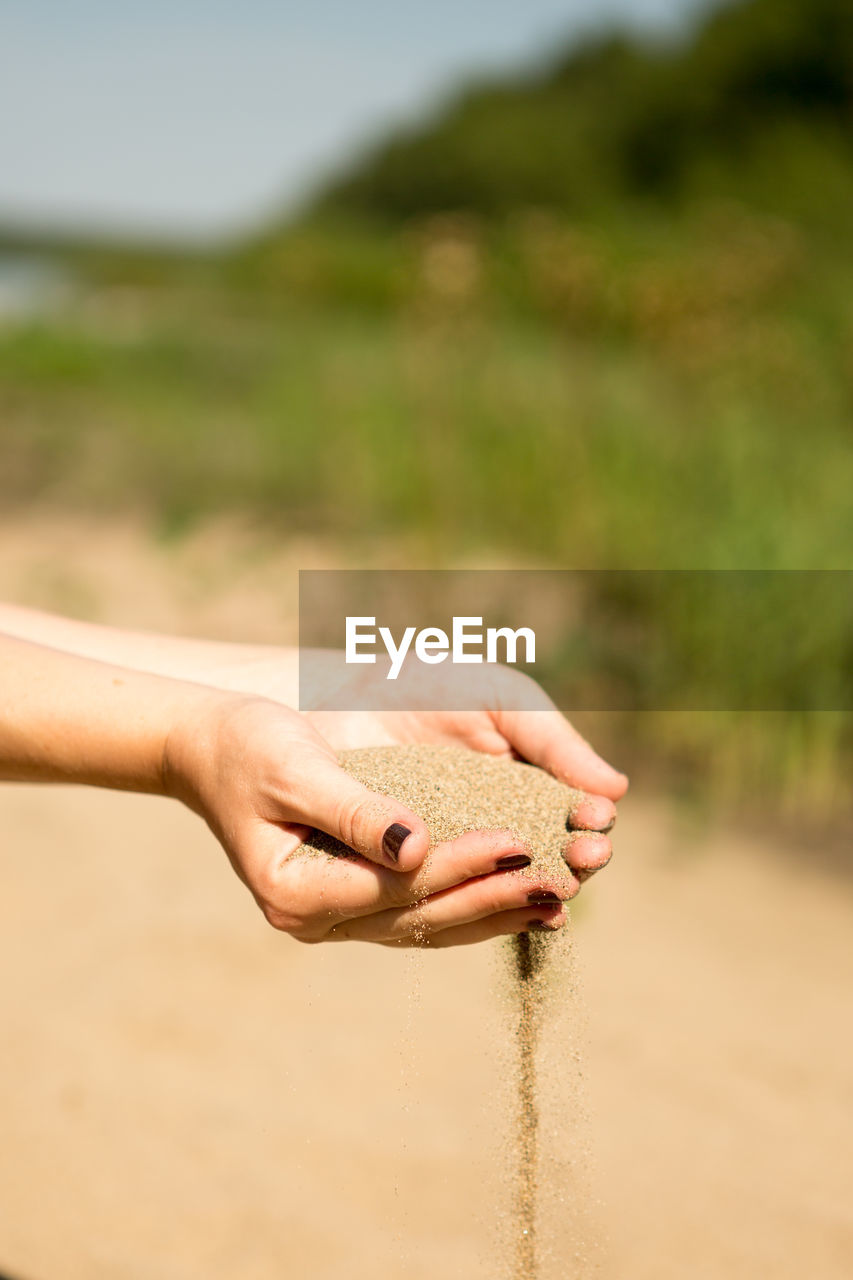 CLOSE-UP OF HANDS HOLDING SAND