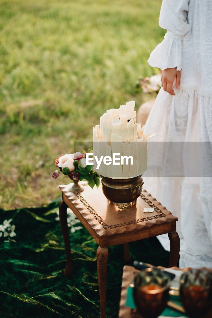 Midsection of woman standing by cake on table 