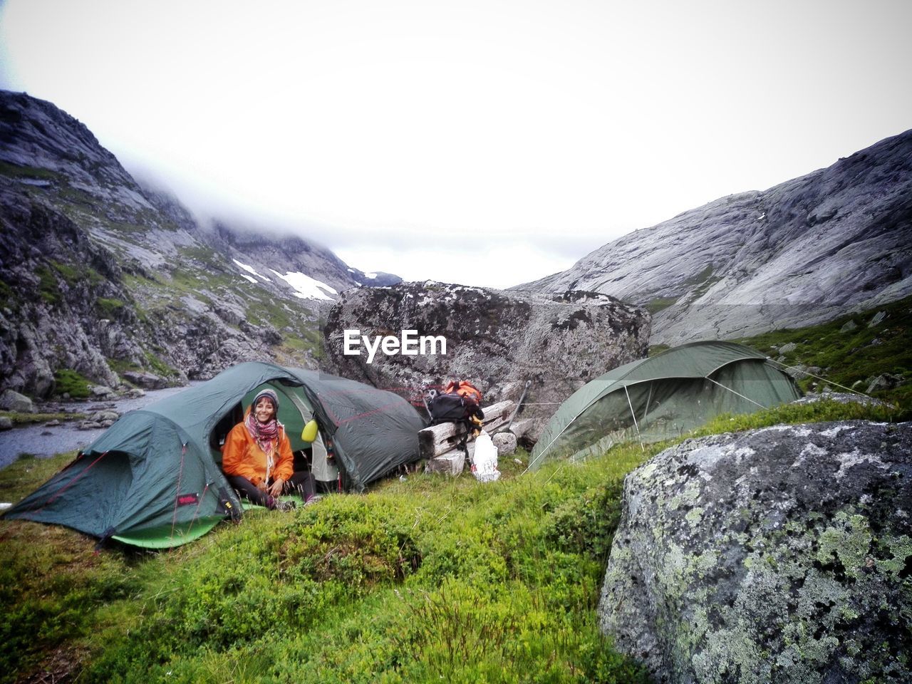 Happy woman sitting in tent against mountain